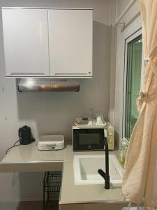 a kitchen with a sink and a microwave at Joyful House in Ban Dan +1 photo