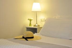 a straw hat sitting on a bed next to a lamp at Cà du Ferrà - Farm and Relax in Bonassola