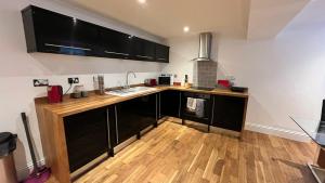 a kitchen with black cabinets and a wooden floor at Flat 1- The Marilyn in Banbury