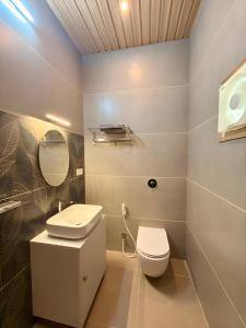 a bathroom with a white toilet and a sink at Evara Stays Coorg in Kushālnagar