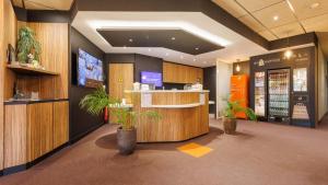 a restaurant lobby with a counter and potted plants at Campanile NATURE - Clermont-Ferrand Nord Riom in Riom