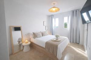 a white bedroom with a bed and a table at Noctua Duquesa Beach 009 in Manilva