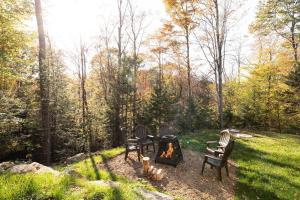 three chairs around a fire pit in a yard at Chalet Boréale with Private Spa & Billiards, Golf & Carling Lake in Brownsburg