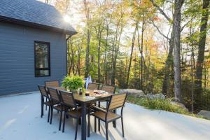 a patio with a table and chairs on a porch at Chalet Boréale with Private Spa & Billiards, Golf & Carling Lake in Brownsburg