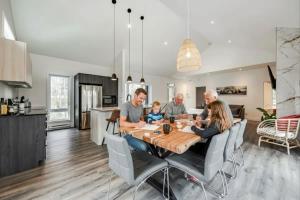 a family sitting around a table in a kitchen at Chalet Boréale with Private Spa & Billiards, Golf & Carling Lake in Brownsburg