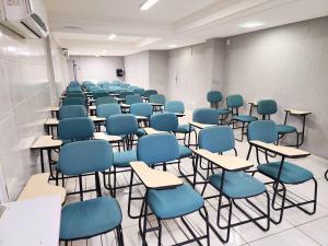 ein Klassenzimmer mit blauen Stühlen und Tischen in einem Raum in der Unterkunft JR Hotel in João Pessoa