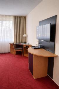 ein Hotelzimmer mit Schreibtisch und Fernseher auf einem Tisch in der Unterkunft Hotel Dresden Neustadt in Dresden