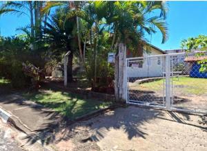 a fence in front of a house with palm trees at Espaço da Iza in São Pedro +6 photos