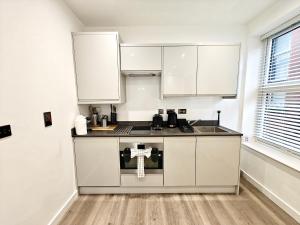 a small kitchen with white cabinets and a sink at Executive 1-Bed Apartment in Town in Bury