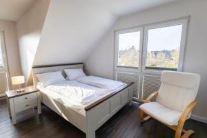 a bedroom with a bed and a chair and two windows at Doppelhaushälfte Op de Geest in Böhl