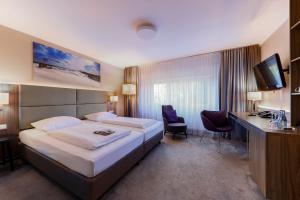 a hotel room with a bed and a desk at Upstalsboom Parkhotel in Emden +38 photos