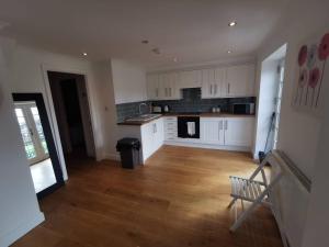 a kitchen with white cabinets and a wooden floor at Flat 12- The Meadow in Banbury