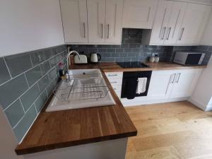 a kitchen with white cabinets and a dish drying rack at Flat 12- The Meadow in Banbury
