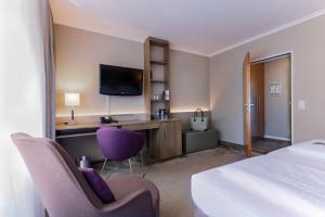 a hotel room with a bed and a desk with two chairs at Upstalsboom Parkhotel in Emden