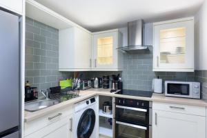 a kitchen with white cabinets and a sink at Perfect 3 Bedroom Accommodation for Contractors! in Banbury