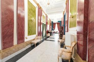 a hallway with chairs and paintings on the walls at Hotel Praga 1885 by Wagnerstays in Prague