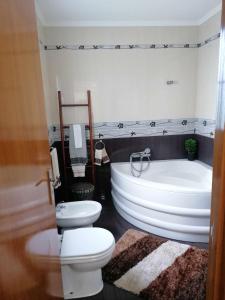 a bathroom with a tub and a toilet and a bath tub at Arco-Iris in Santo António +10 photos