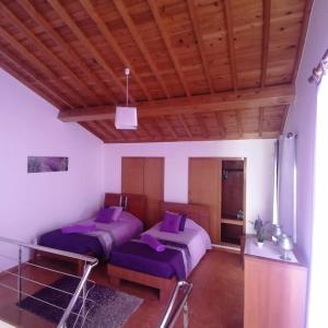 two beds in a room with purple pillows at Arco-Iris in Santo António