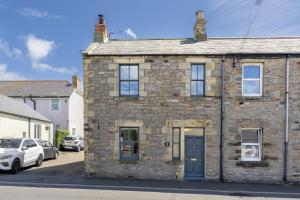an old stone house with a blue door on a street at Northern Hideaways St Cuthberts, Seahouses in Seahouses