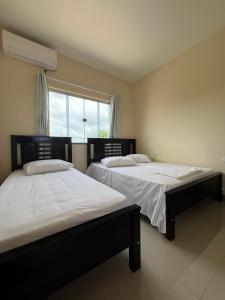two twin beds in a room with a window at Hotel Brilhante 2 in Itacarambi
