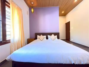 a bedroom with a large white bed with two pillows at Evara Stays Coorg in Kushālnagar