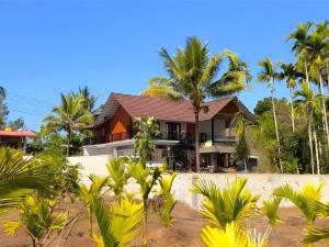 a house on the beach with palm trees at Evara Stays Coorg in Kushālnagar