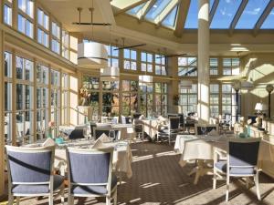 a restaurant with white tables and chairs and windows at Interalpen-Hotel Tyrol in Seefeld in Tirol