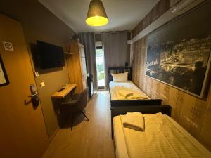 a room with two beds and a desk and a television at Boutique Hotel Sena in Berlin