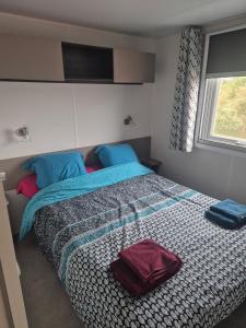 a bedroom with a large bed with blue pillows at Mobil-Home L'Escale-MH34 Les Sables du Midi in Sérignan