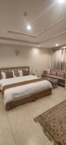 a large bedroom with a large bed and a couch at عمارة النفيسة السكنية in Unayzah