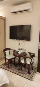 a living room with a table and chairs and a flat screen tv at عمارة النفيسة السكنية in Unayzah +4 photos