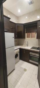 a kitchen with a white refrigerator and a dishwasher at عمارة النفيسة السكنية in Unayzah