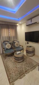 a living room with two chairs and a flat screen tv at عمارة النفيسة السكنية in Unayzah