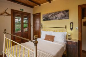 a bedroom with a bed with white sheets and a window at Antiga Fábrica da Manteiga by An Island Apart in Arco da Calheta