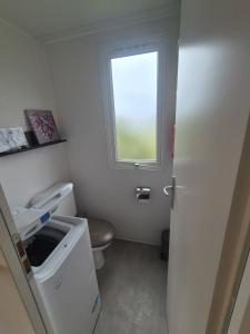 a small bathroom with a toilet and a window at Mobil-Home L'Escale-MH34 Les Sables du Midi in Sérignan +3 photos