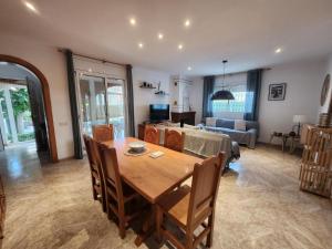 a dining room and living room with a table and a couch at Villa Xaloc piscine privée in Les tres Cales
