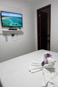 a bedroom with a bed with a tv on the wall at Pousada Maragobeach Suits in Maragogi