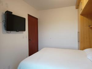 a bedroom with a bed and a tv on the wall at Piemonte Flat Serra Negra in Serra Negra