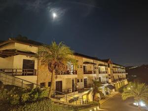 a building with palm trees in front of it at night at Piemonte Flat Serra Negra in Serra Negra