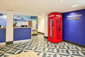 a red phone booth in a room with a blue wall at Thistle London Heathrow Terminal 5 in Hillingdon