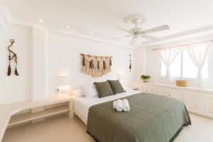 a white bedroom with a bed and a ceiling fan at Mansion Mauresque in Playa del Carmen