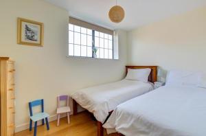 a bedroom with two beds and a chair and a window at 2 Bed in Swanage oc-wy412 in Swanage