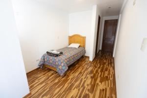 a bedroom with a bed and a wooden floor at Casa completa, 5 dormitorios y jardín in Ayacucho