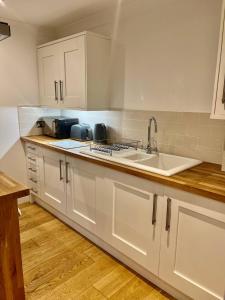 a kitchen with white cabinets and a sink at Flat 8- Garden Square in Banbury +4 photos
