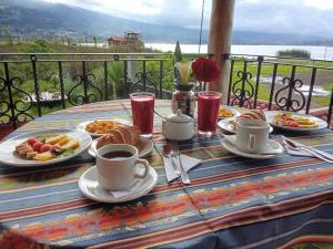 a table with plates of food and cups of coffee at Brisas Del Lago San Pablo in Otavalo