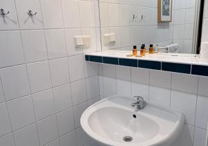 a white bathroom with a sink and a mirror at Hotel Flora in Łódź +33 photos