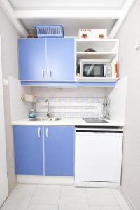 a small kitchen with blue cabinets and a microwave at LES MARINES 2 - Villa en résidence avec piscine à 2 pas de la plage - Clim - parking in Saint-Cyprien +7 photos