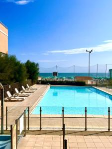 a swimming pool with chairs and the ocean in the background at Apartament Mare e Sole z basenem i przy plaży in Marotta