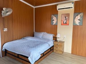 a bedroom with a bed with a wooden wall at Mộc Homestay - Mộc Châu in Mộc Châu