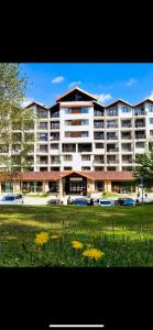 a large apartment building with yellow flowers in the grass at Borovets luxury studio in Samokov
